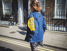 woman in blue jacket walking on sidewalk during daytime